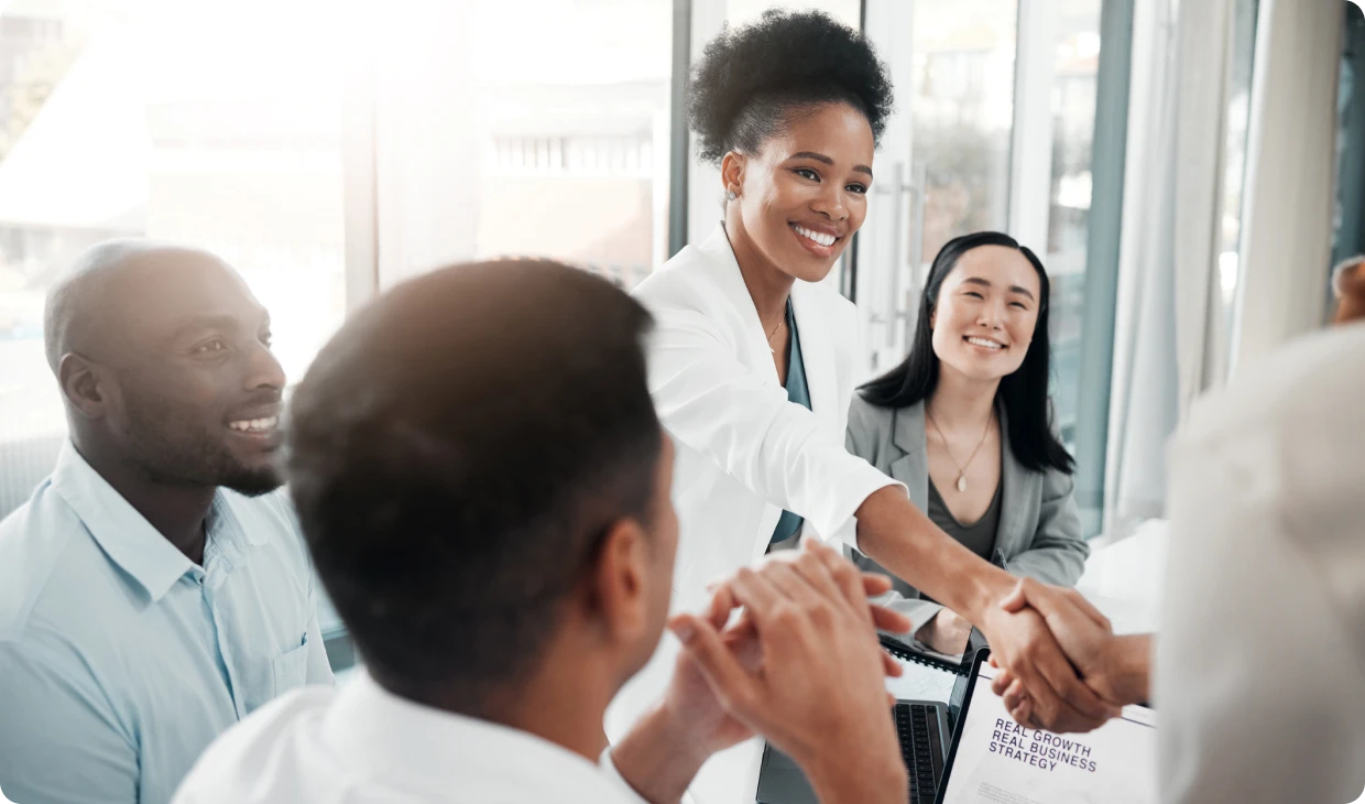 Smiling colleagues shaking hands in meeting.