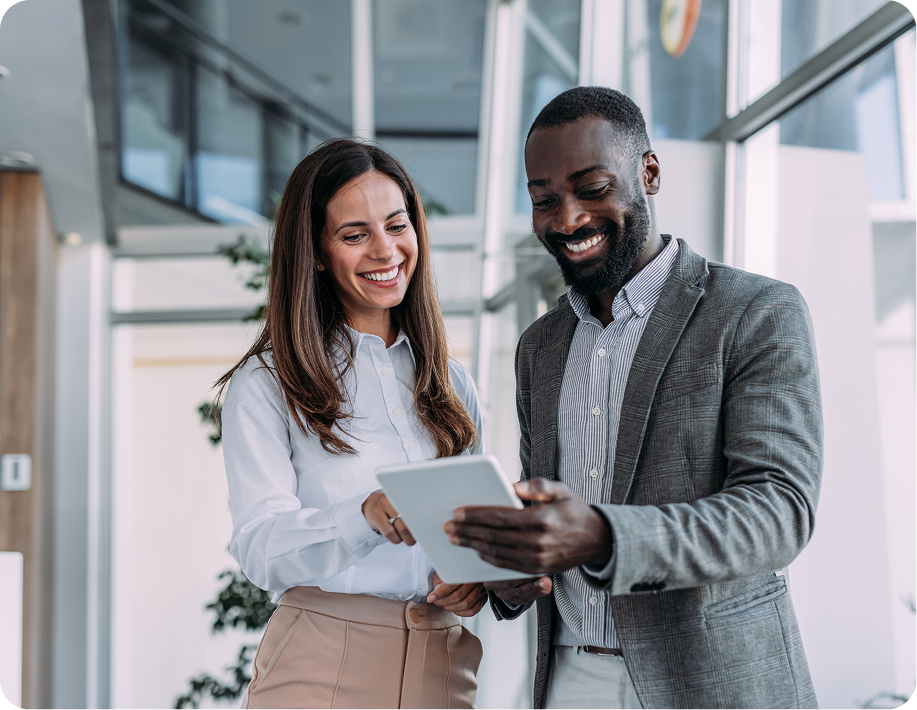 Two colleagues smiling and looking at tablet.
