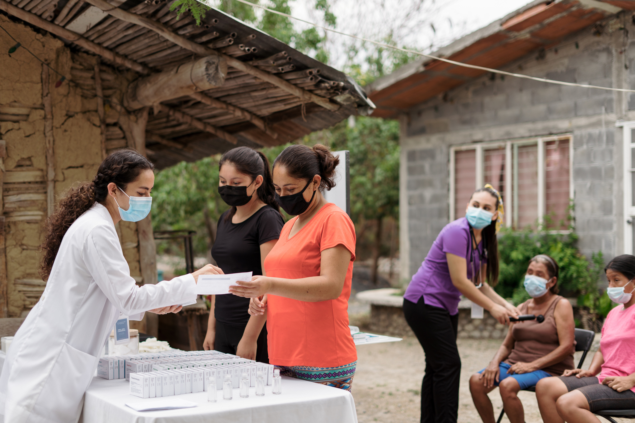 Female health practitioners doing a medical brigade in remote rural area and wearing face masks.