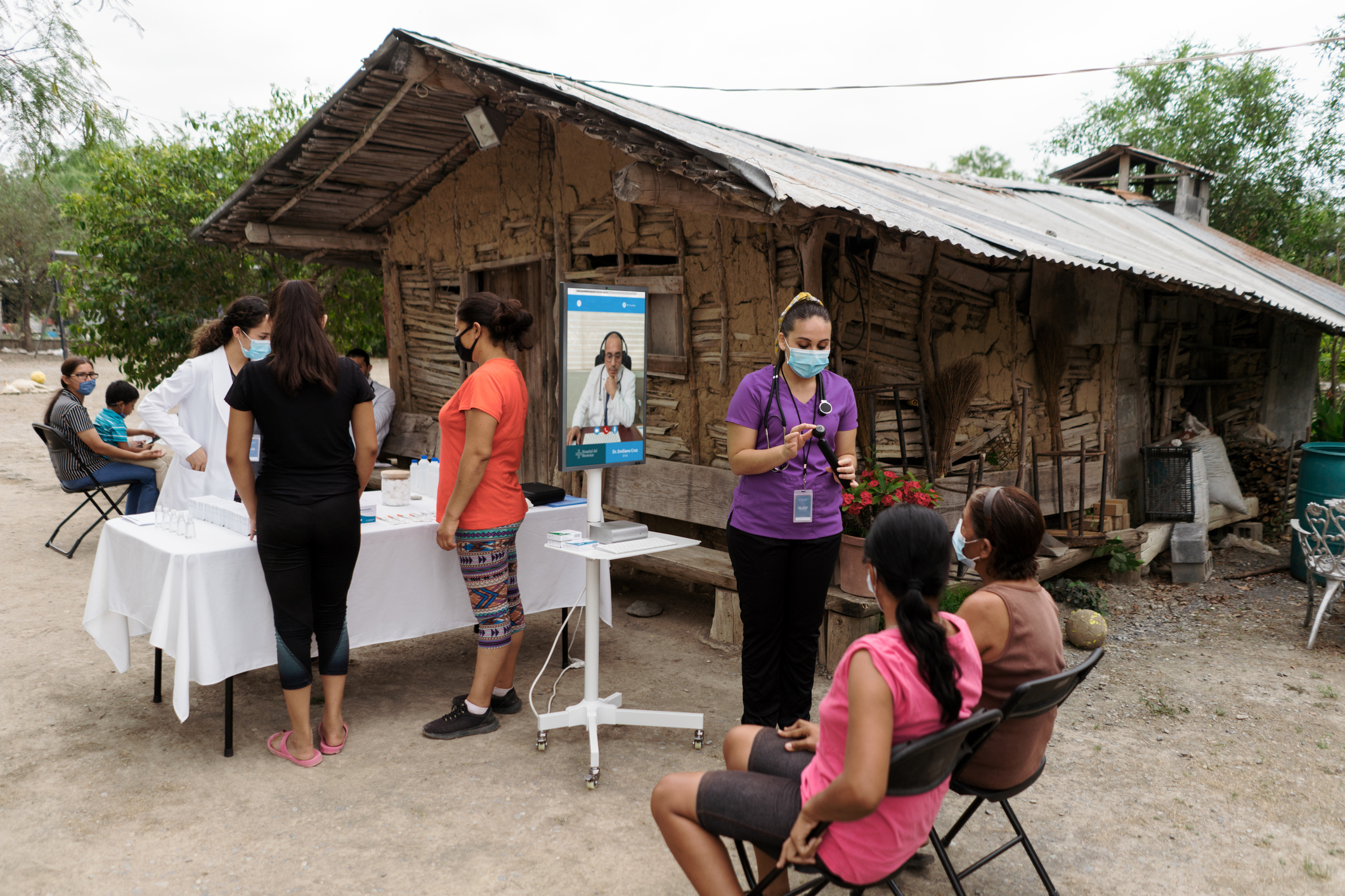 Latin people on a medical brigade in a rural area and teleconsulting a senior doctor with a nurse and a wireless device.